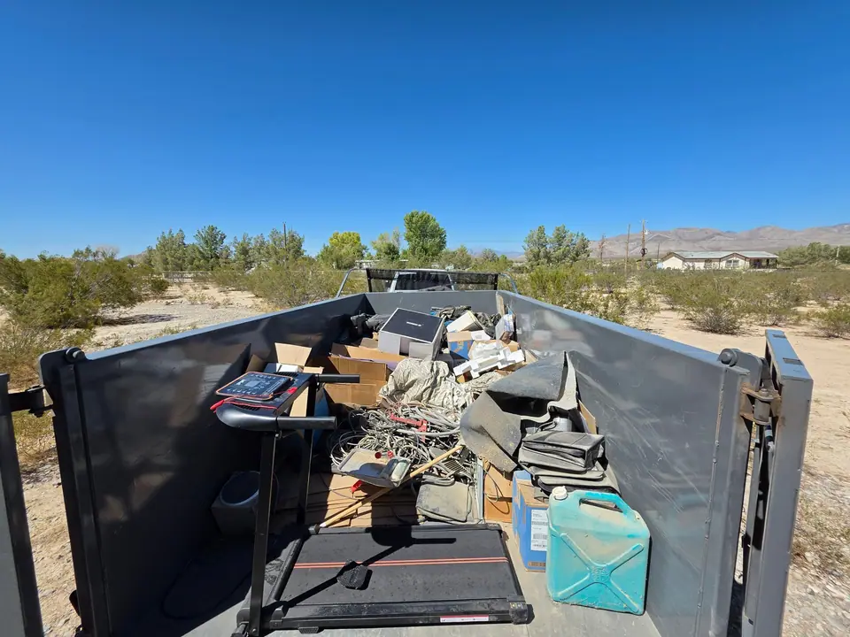 Dump trailer full of a treadmill, chairs and garage overflow on a desert lot