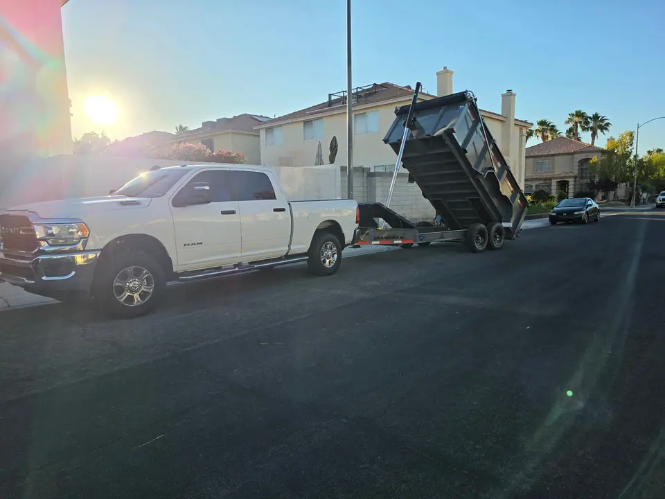 Legend Hauling white pickup and dump trailer with the bed raised at sunrise on a Las Vegas valley street